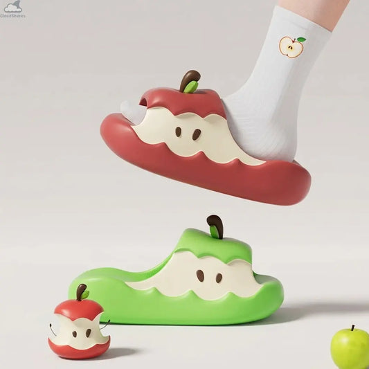 Model wearing a red Apple Cloud Slide with white apple sock floating above a green slide, featuring soft cloudsharks cushion comfort style in a clean studio setting.