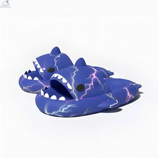 Perspective angle view of a pair of royal blue Lightning Shark Slides featuring bright purple and white electric lightning strikes and white teeth.
Perspective view of royal blue Lightning Shark Slides with electric purple lightning pattern, open shark mouth, and 4cm cushioned cloud slides sole.
