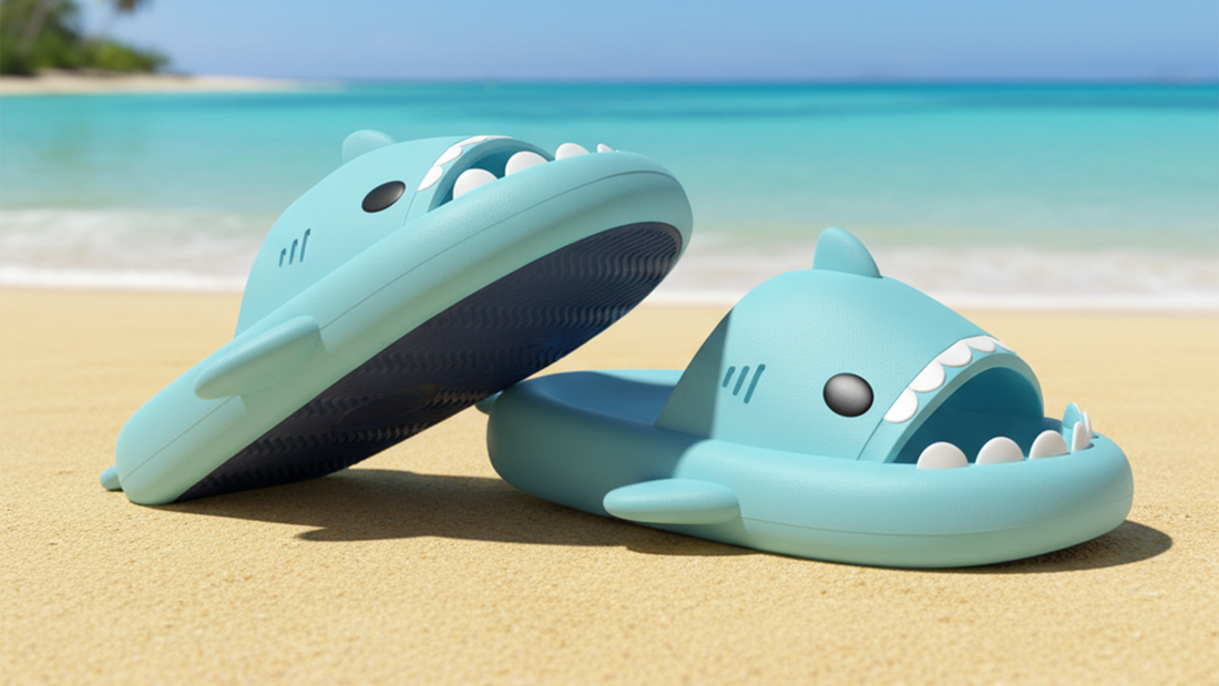First-person view of feet wearing pastel blue CloudSharks slides on a white sandy beach with turquoise waves, showcasing comfortable and stylish summer footwear for 2026.