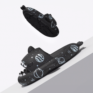 Two black Cosmic Shark Slides with space patterns. One slide is elevated, showing the anti-slip sole. The image highlights the sleek profile and the thick, supportive 4cm sole.