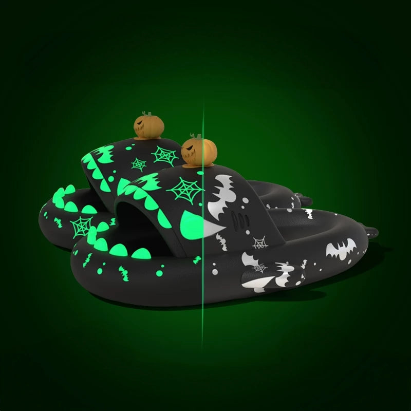 Black Cloudsharks Halloween shark slides with glowing green spiderwebs, bats, teeth, and 3D pumpkin toppers showing day and night glow effects. Black Halloween Shark Slides featuring a 3D jack-o'-lantern pumpkin charm topper, bat and spiderweb prints, and glow-in-the-dark teeth and accents shown in a split-screen daytime/nighttime comparison.