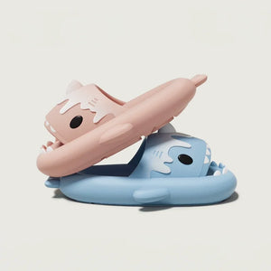 A pair of pink Cloudsharks shark slides stacked on top of a blue pair, showcasing the soft material and playful design of these comfy sandals.