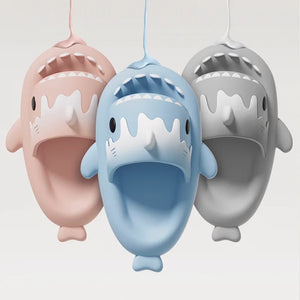 Cloudsharks shark slippers in pastel pink, ocean blue, and gray colors, hanging display with adorable shark design – comfy and trendy slides.