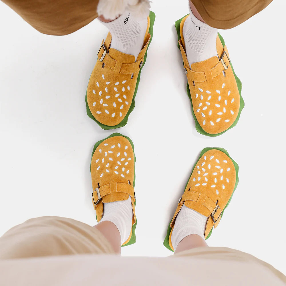 Top-down view of two people wearing matching burger house slippers with sesame seed details, perfect for fans of cloudsharks and cozy food-themed footwear.