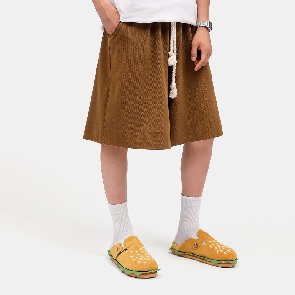 Close up of a model’s legs featuring the layered "lettuce and bun" design of the burger slippers, built with a supportive cork footbed similar to premium cloudsharks.