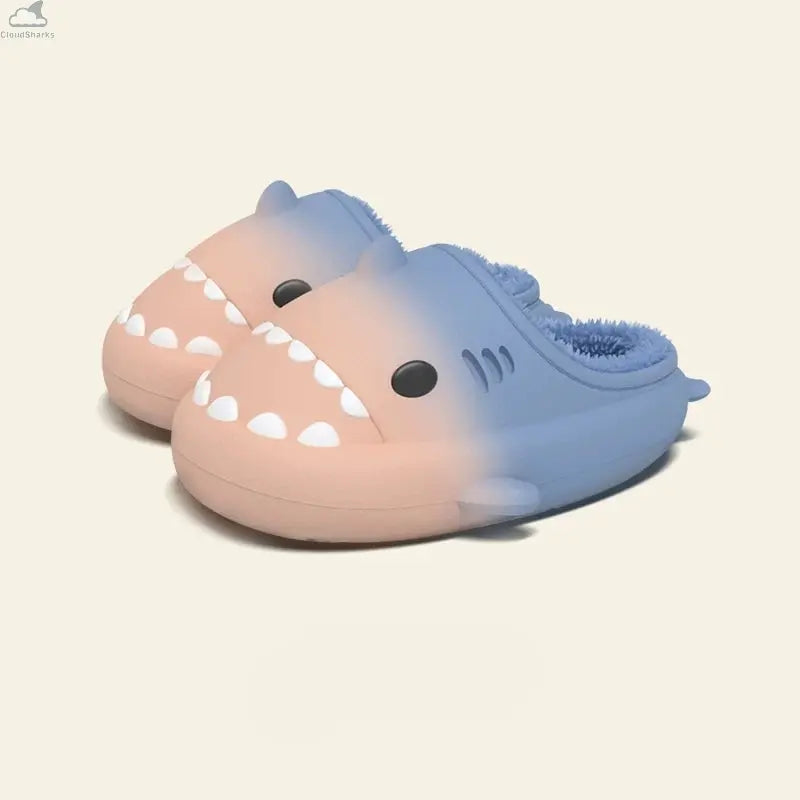 A pair of Gradient Winter Shark Slides showing a warm peach-pink-to-sky-blue gradient with a soft blue fleece interior. Pair of peach pink and sky blue gradient shark slides featuring plush blue fleece lining, cloudsharks waterproof winter house slippers.