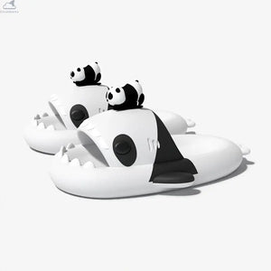 Side-angle view of a pair of white and black Panda Family Shark Slides displaying the 3D mini panda toppers, side fins, and sharp shark teeth. Side perspective of black and white Panda Family Shark Slides by Cloudsharks showing thick cushioned cloud soles, shark teeth, and a 3D mini panda figure on top.