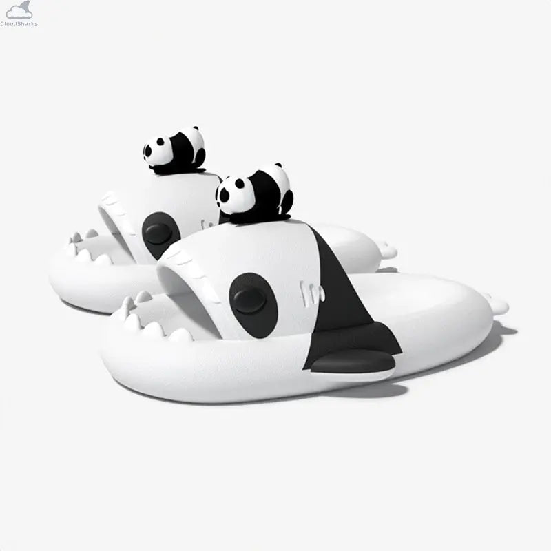 Side-angle view of a pair of white and black Panda Family Shark Slides displaying the 3D mini panda toppers, side fins, and sharp shark teeth. Side perspective of black and white Panda Family Shark Slides by Cloudsharks showing thick cushioned cloud soles, shark teeth, and a 3D mini panda figure on top.