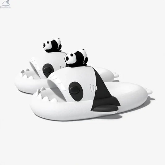 Side-angle view of a pair of white and black Panda Family Shark Slides displaying the 3D mini panda toppers, side fins, and sharp shark teeth. Side perspective of black and white Panda Family Shark Slides by Cloudsharks showing thick cushioned cloud soles, shark teeth, and a 3D mini panda figure on top.