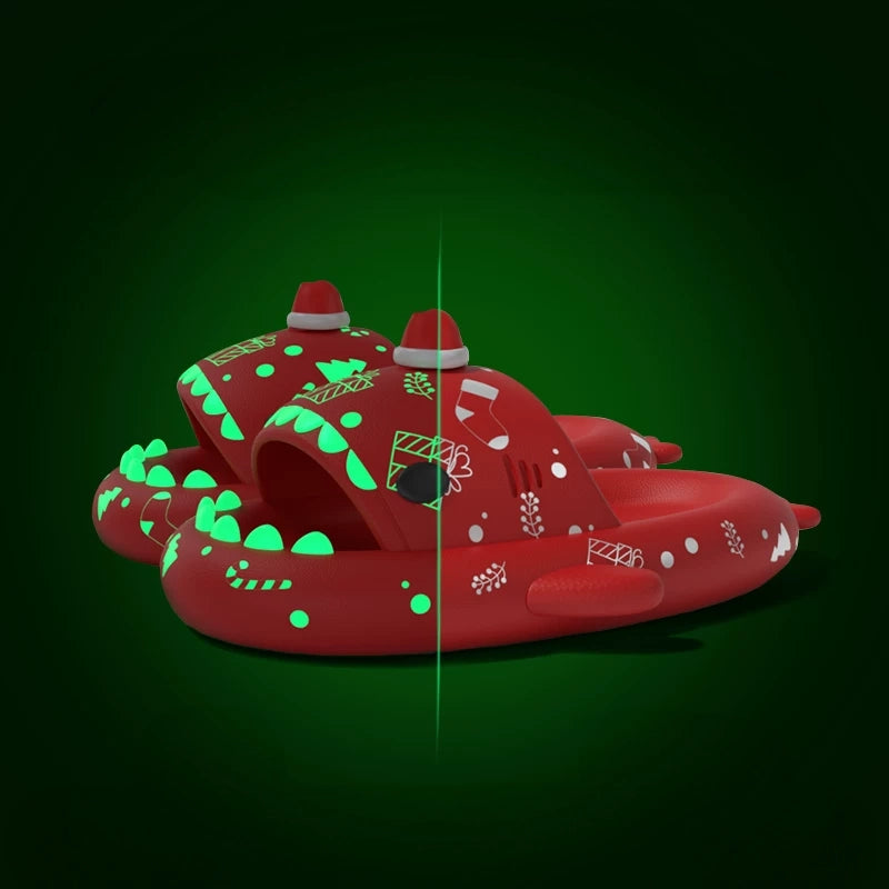 Red Cloudsharks holiday shark slippers featuring 3D Santa hats, festive stocking patterns, and light-up green shark teeth in dark and light settings. Red Christmas Holiday Shark Slides featuring a 3D mini Santa hat topper, gift boxes, stockings, snowflake-style holiday prints, and glowing green teeth in a split-screen light comparison.