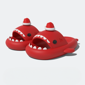 Pair of red shark slippers with white teeth and a red and white Santa hat on the fin, against a white background. Perfect for the holidays.