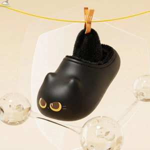 Black Cloudsharks cat slipper hanging from a yellow clothesline by an orange clothespin, showing its pull-out black fleece inner lining, frosted glass panels, and water-bubble decor on a beige studio background.