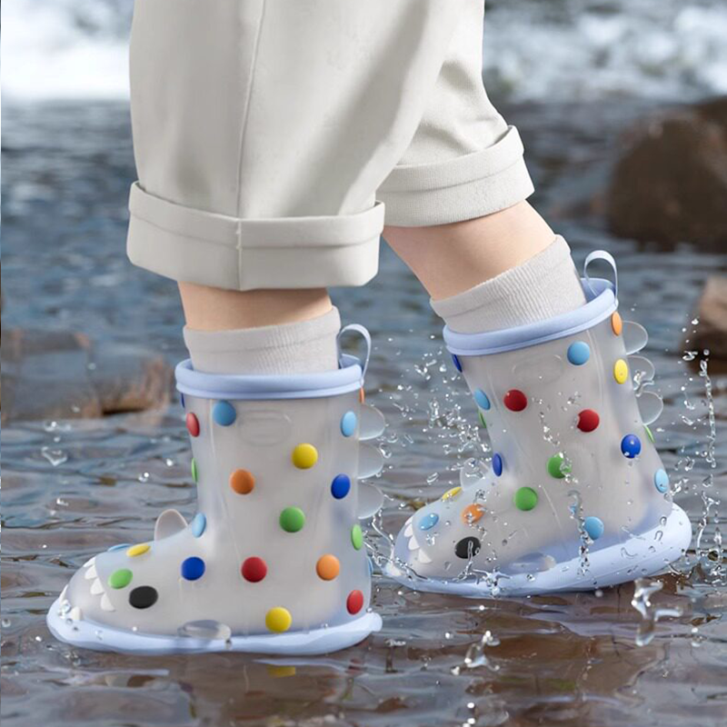 Child walking through water in rainbow dot shark rain boots, lightweight polka dot design with shark teeth, non-slip sole, perfect for rainy adventures.
