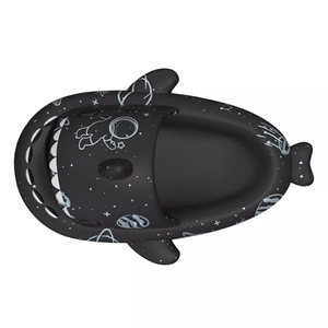 Top-down view of a single black Cosmic Shark Slide, showcasing the deep, comfortable footbed and the shark's mouth design with white teeth. Space patterns are visible on the footbed and exterior.