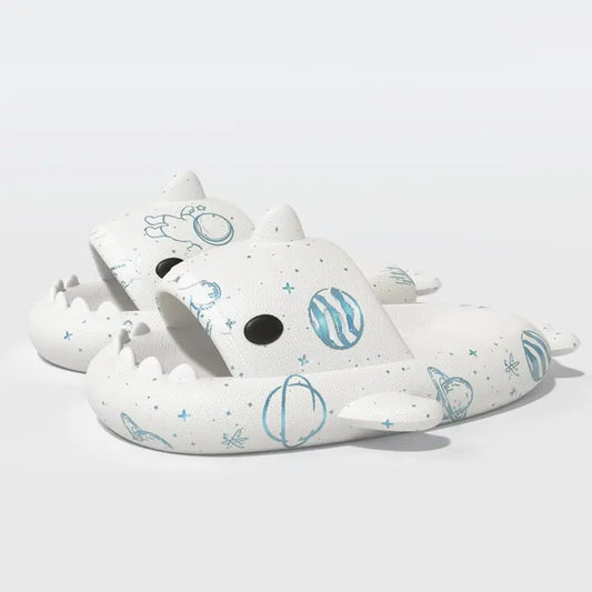 White Cosmic Shark Slides with space-themed designs featuring planets and stars, made from soft EVA material. Available now at CloudSharks.shop.