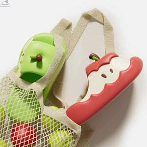 Red and green Apple Cloud Slides tucked into a mesh market bag next to fresh apples, featuring cute cloudsharks cushion comfort design.